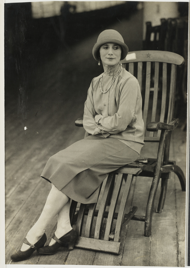 Anna Pavlova sitting very still on a deck chair.